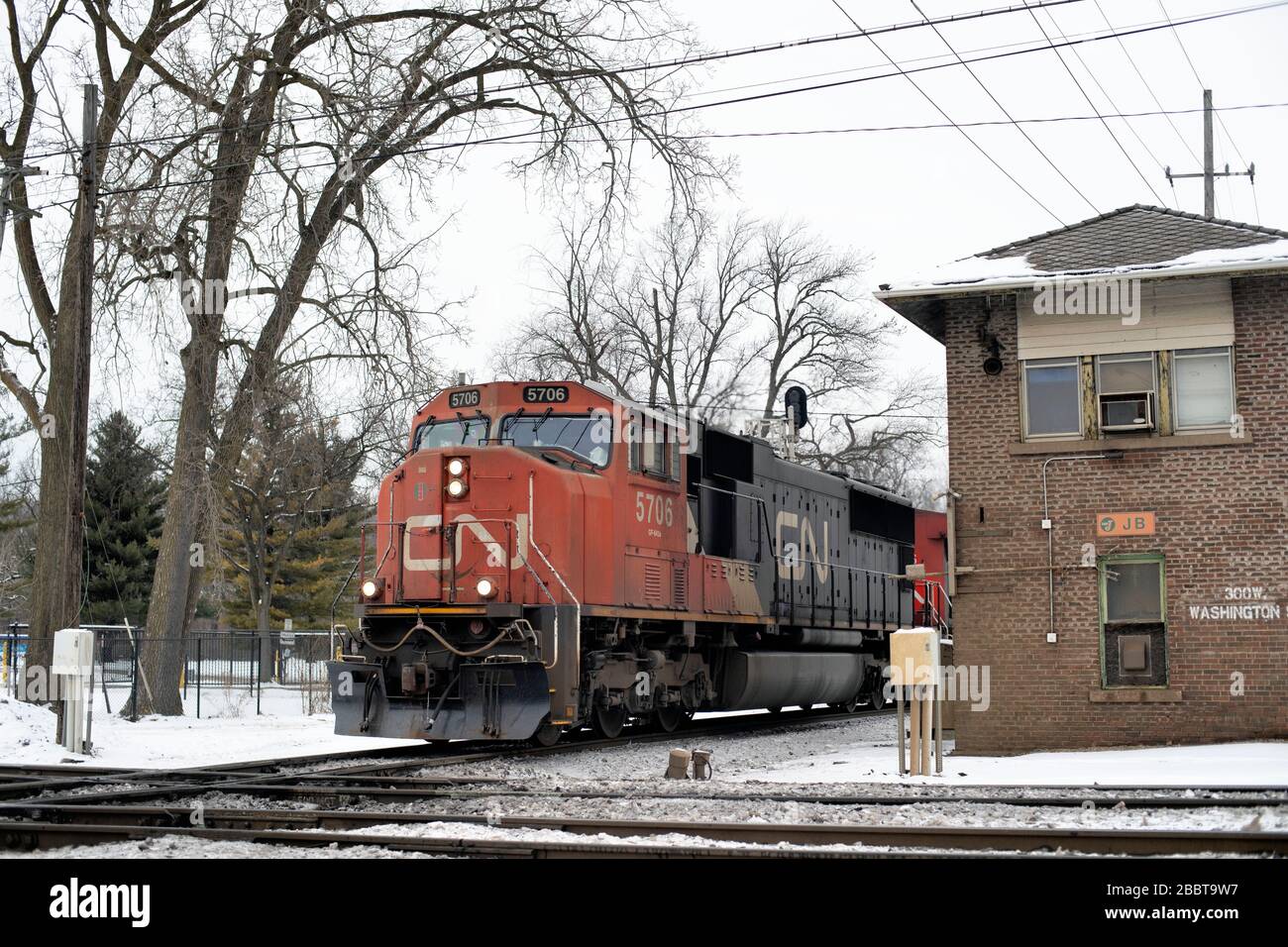 West Chicago, Illinois, USA. Ein Güterzug der Canadian National Railways, der einen Kontrollturm passiert, bevor er eine Kreuzung überquert. Stockfoto