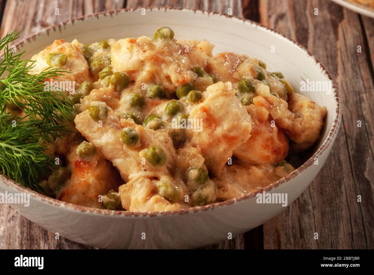 Geschmortes Hühnerfilet mit grünen Erbsen auf einem Holztisch Stockfoto