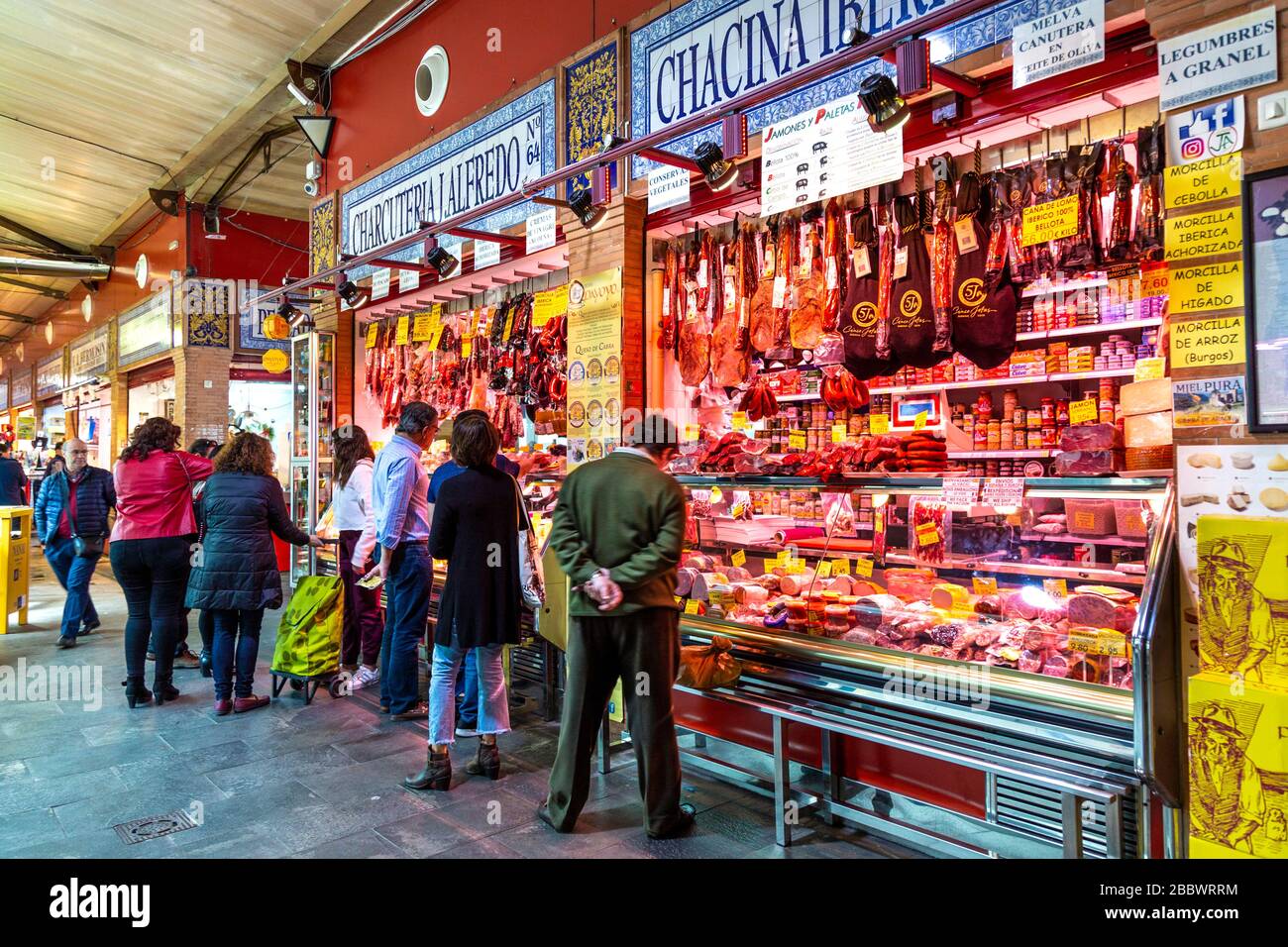 Menschen, die in einem Metzger- und DELI-Stall am Triana-Markt (Mercado de Triana), Sevilla, Andalusien, Spanien einkaufen Stockfoto