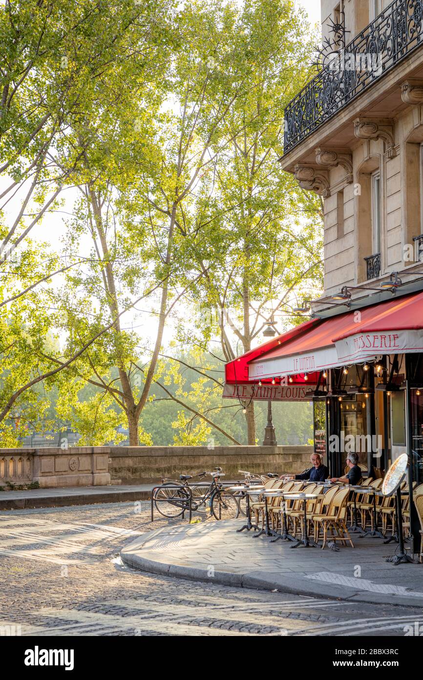 Frühmorgendliches Sonnenlicht im Café Le Lutetia und die Bäume, die die seine, Ile Saint Louis, Paris, Frankreich säumen Stockfoto