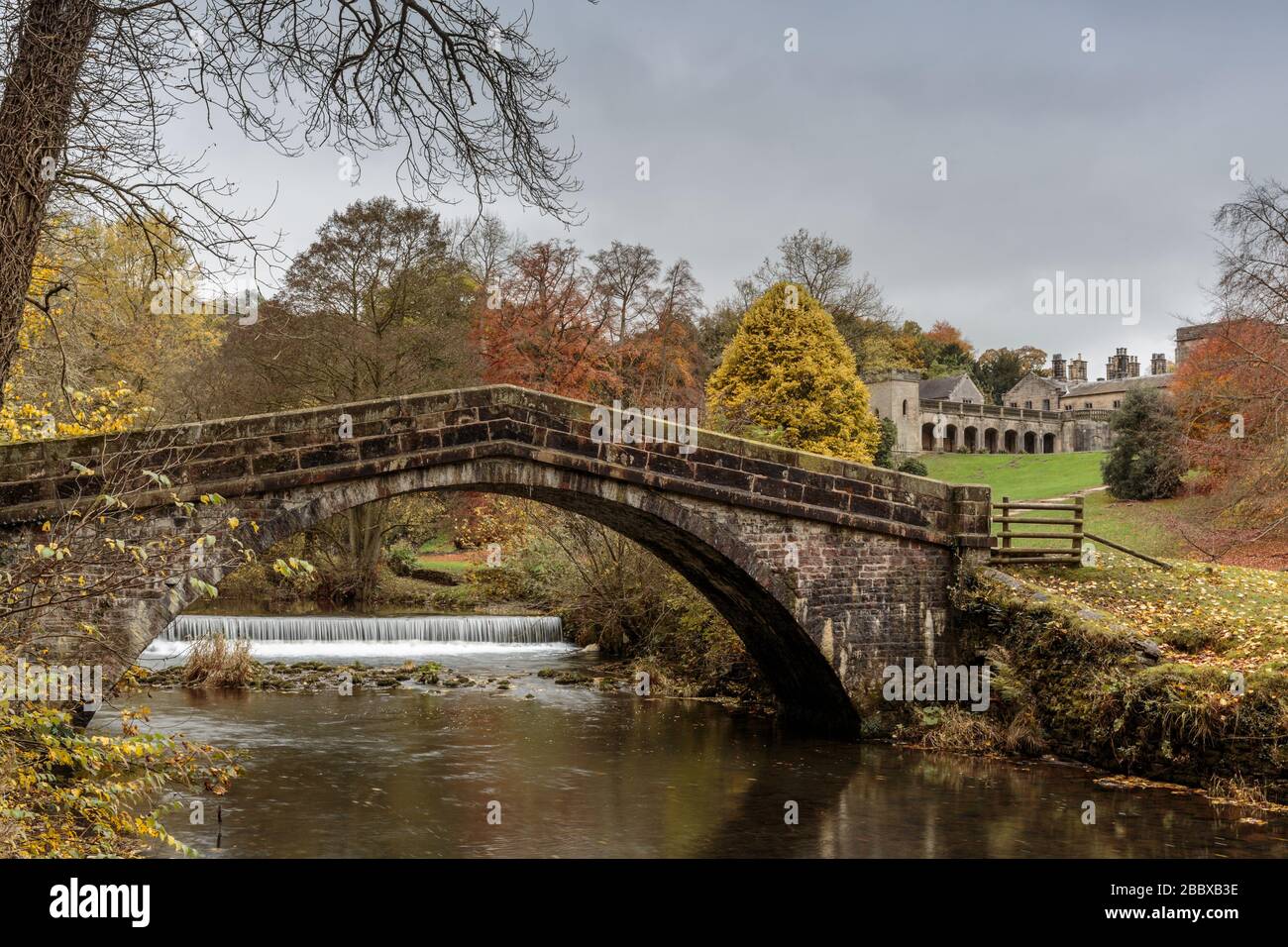 Steinbrücke über den Fluss vielfältig mit Ilam Hall im Hintergrund., Ilam, Staffordshire, Peak District National Park, England, Großbritannien Stockfoto