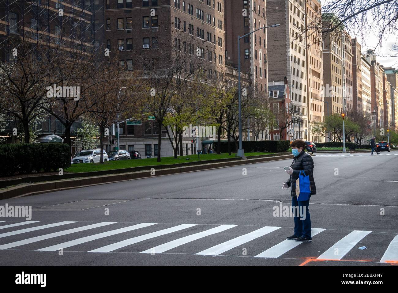 New York, USA. April 2020. Die Menschen tragen Gesichtsmasken, während sie während der Coronavirus-Krise warten, eine ungewöhnlich leere Park Avenue in New York zu überqueren. Kredit: Enrique Shore/Alamy Live News Stockfoto