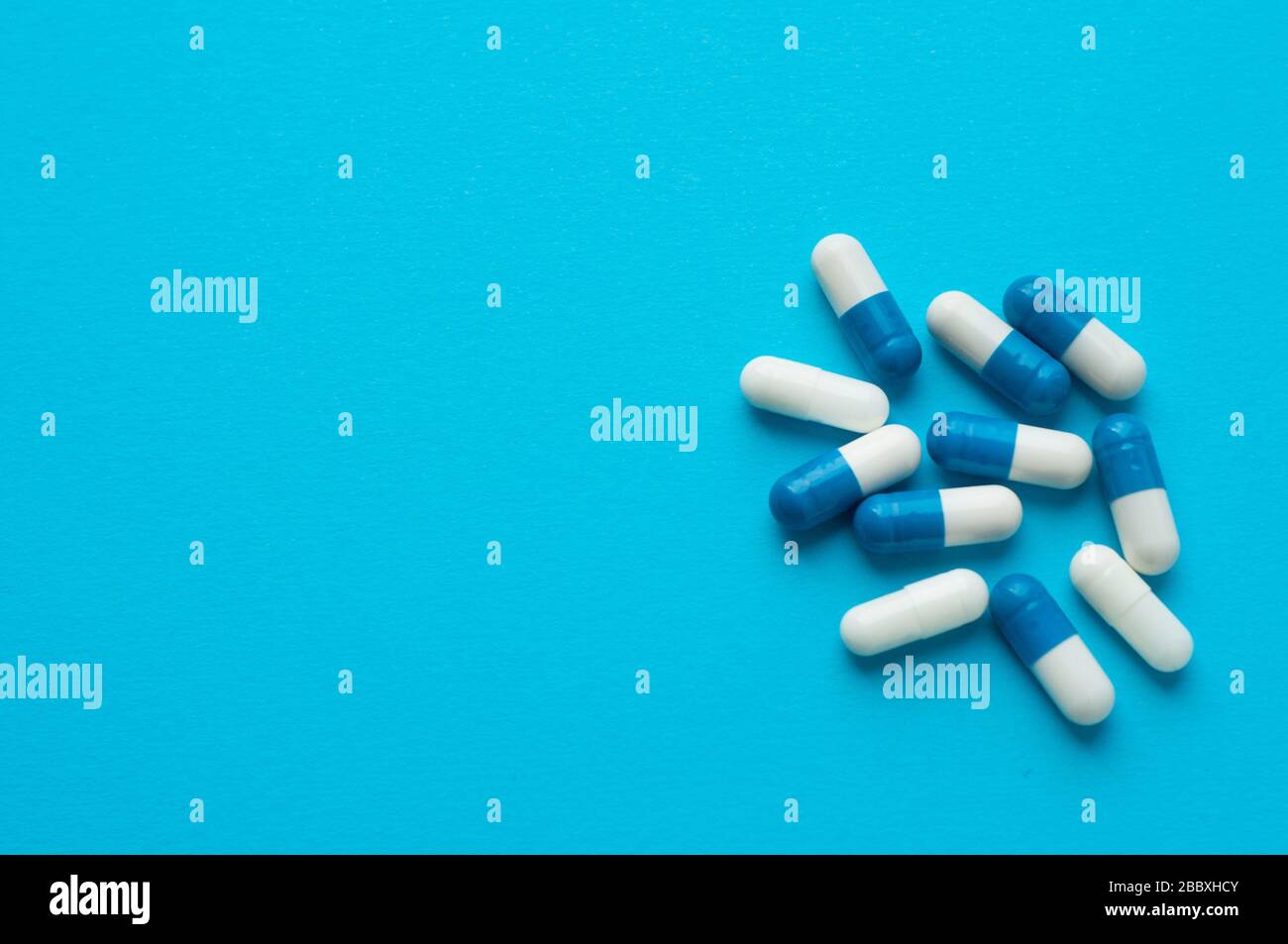 Antivirale Kapseln, Tabletten zur Behandlung auf blauem Grund. Weiß-blaue Kapseln. Flache Lage, Draufsicht Stockfoto