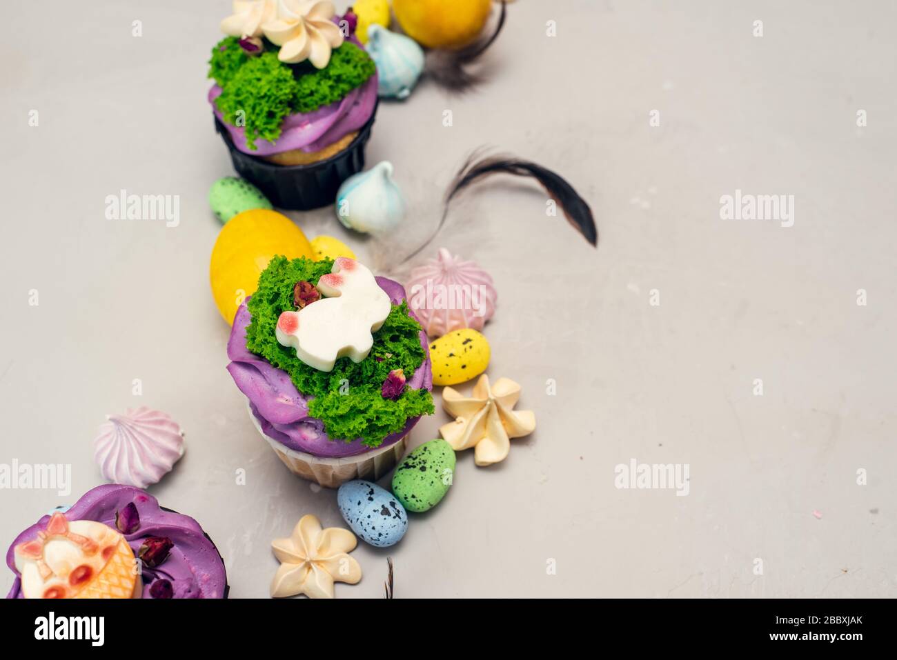 Orthodoxe Osterkuchen, die mit Sahne in Form von Gras und weißen Schokoladenfigurinen verziert sind. Osterhase Cupcakes, Ostern Essen Handwerksidee für Kinder. Stockfoto