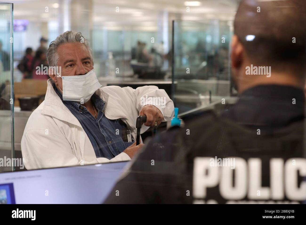 Beamte des US-amerikanischen Zoll- und Grenzschutzamtes für Feldeinsätze sehen internationale Passagiere aus, die am Dulles International Airport in Dulles, Virginia, am 13. März 2020 ankommen. Als Reaktion auf die Coronavirus-Pandemie (COVID-19) haben CBP-Beamte begonnen, persönliche Schutzausrüstung (PSA) zu tragen, während sie mit Passagieren interagieren, die aus dem Ausland ankommen. Viele Passagiere haben auch PSA gespendet, um sich und andere auf ihren Reisen zu schützen. Stockfoto