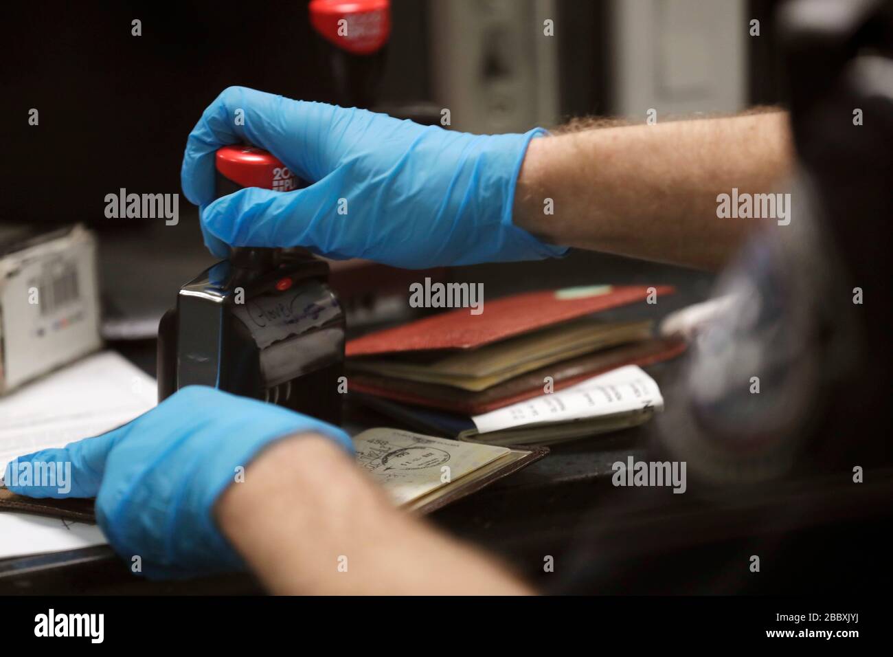 Beamte des US-amerikanischen Zoll- und Grenzschutzamtes für Feldeinsätze sehen internationale Passagiere aus, die am Dulles International Airport in Dulles, Virginia, am 13. März 2020 ankommen. Als Reaktion auf die Coronavirus-Pandemie (COVID-19) haben CBP-Beamte begonnen, persönliche Schutzausrüstung (PSA) zu tragen, während sie mit Passagieren interagieren, die aus dem Ausland ankommen. Viele Passagiere haben auch PSA gespendet, um sich und andere auf ihren Reisen zu schützen. Stockfoto