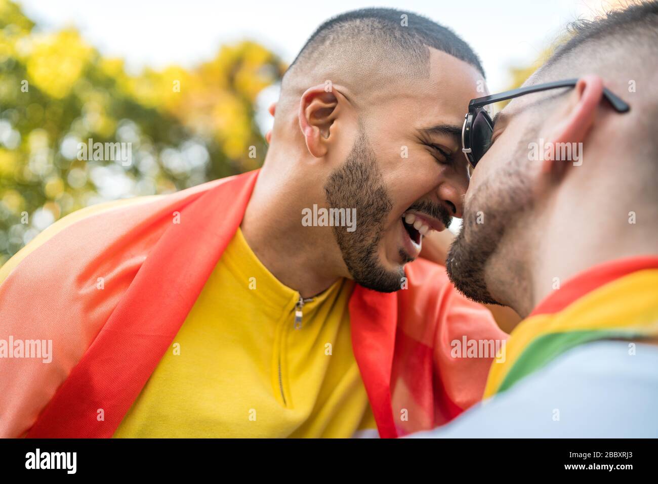 Portrait von jungen homosexuellen Paar umfassend und zeigen ihre Liebe mit Regenbogen Flagge in der Straße. LGBT und liebe Konzept. Stockfoto