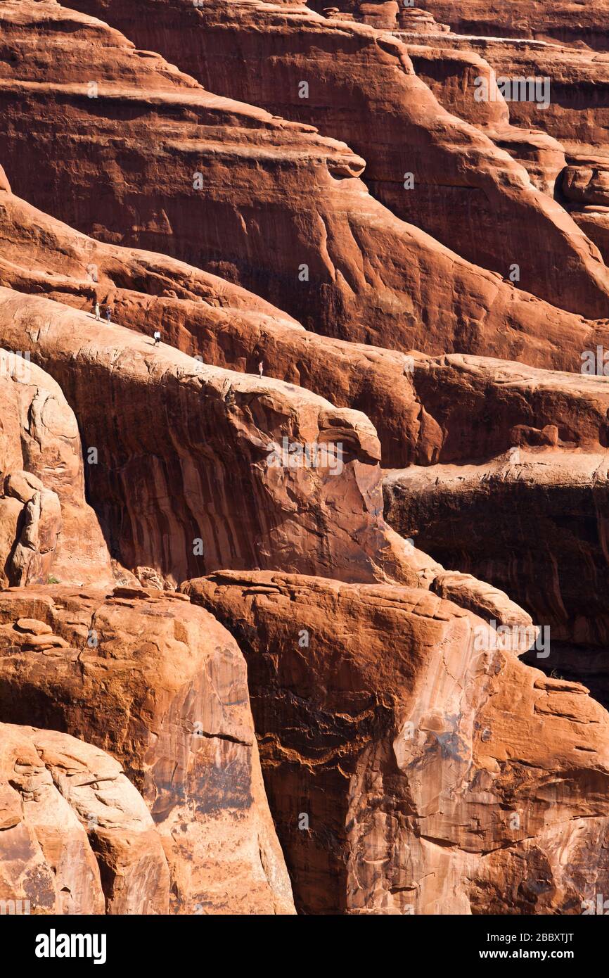 Vier Personen auf einer Finne aus Sandstein im Devils Garden, Arches National Park, Utah. Stockfoto