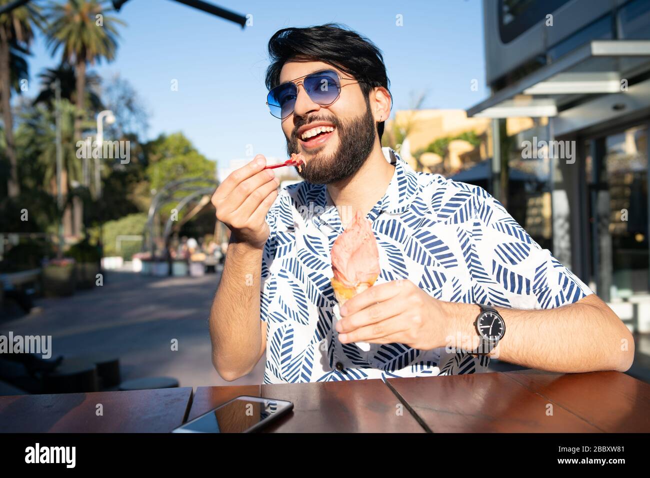 Porträt eines jungen Mannes mit sonnigem Wetter beim essen ein Eis im Freien. Stockfoto