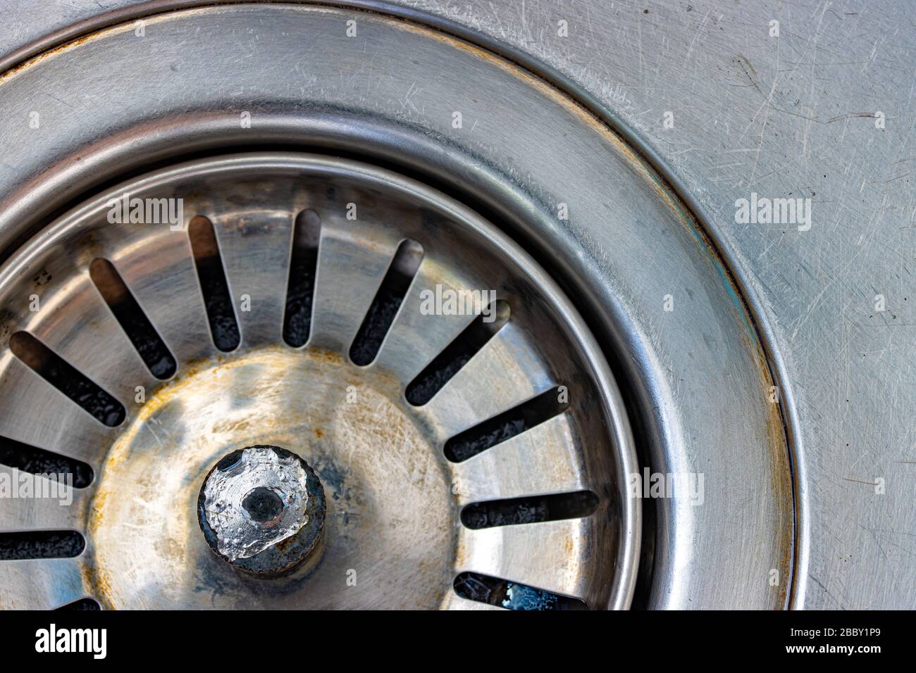 Ein Metallwaschbecken mit Ablaufloch, Makroansicht. Mechanisch verstellbare Ablassschraube in der Nähe. Stockfoto