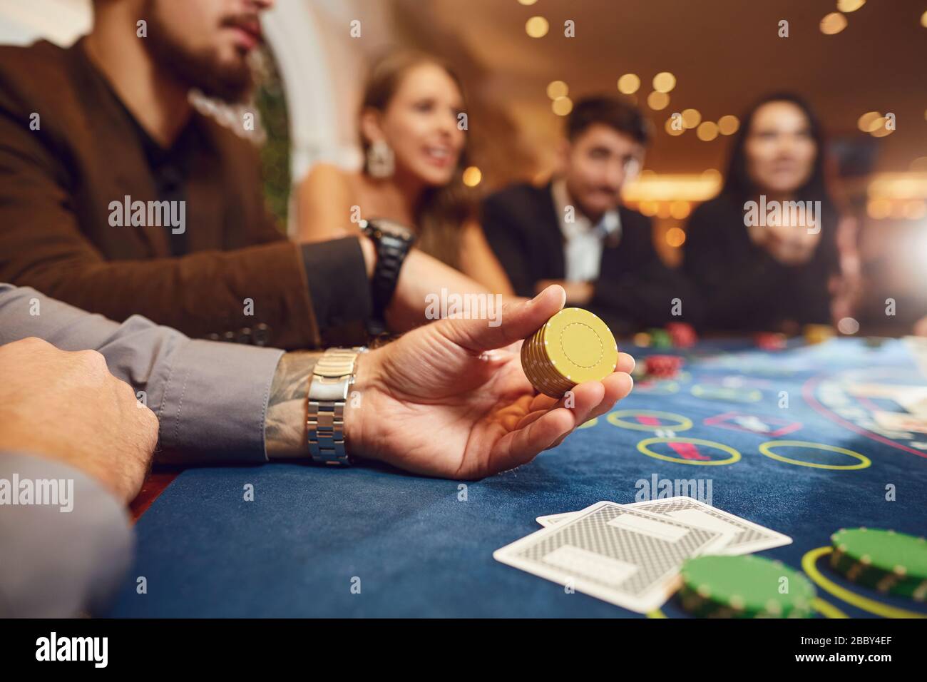 Chips in den Händen eines männlichen Roulettespielers im Casino-Hintergrund. Stockfoto