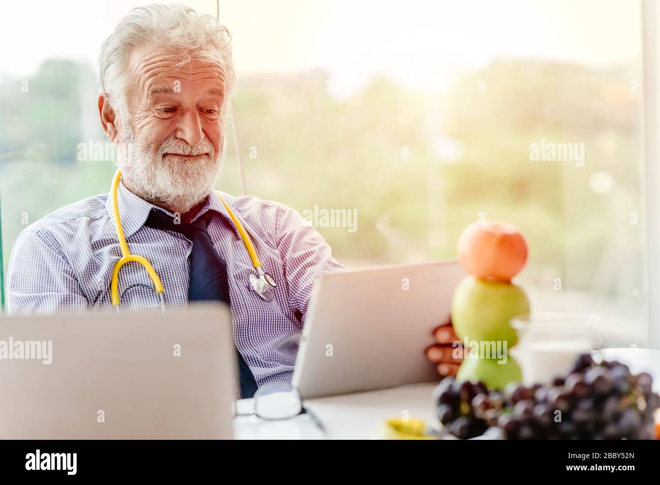 Professioneller Ernährungsberater Arzt Happy Working am Schreibtisch mit obstapfel und Trauben empfehlen, gesund zu essen. Stockfoto