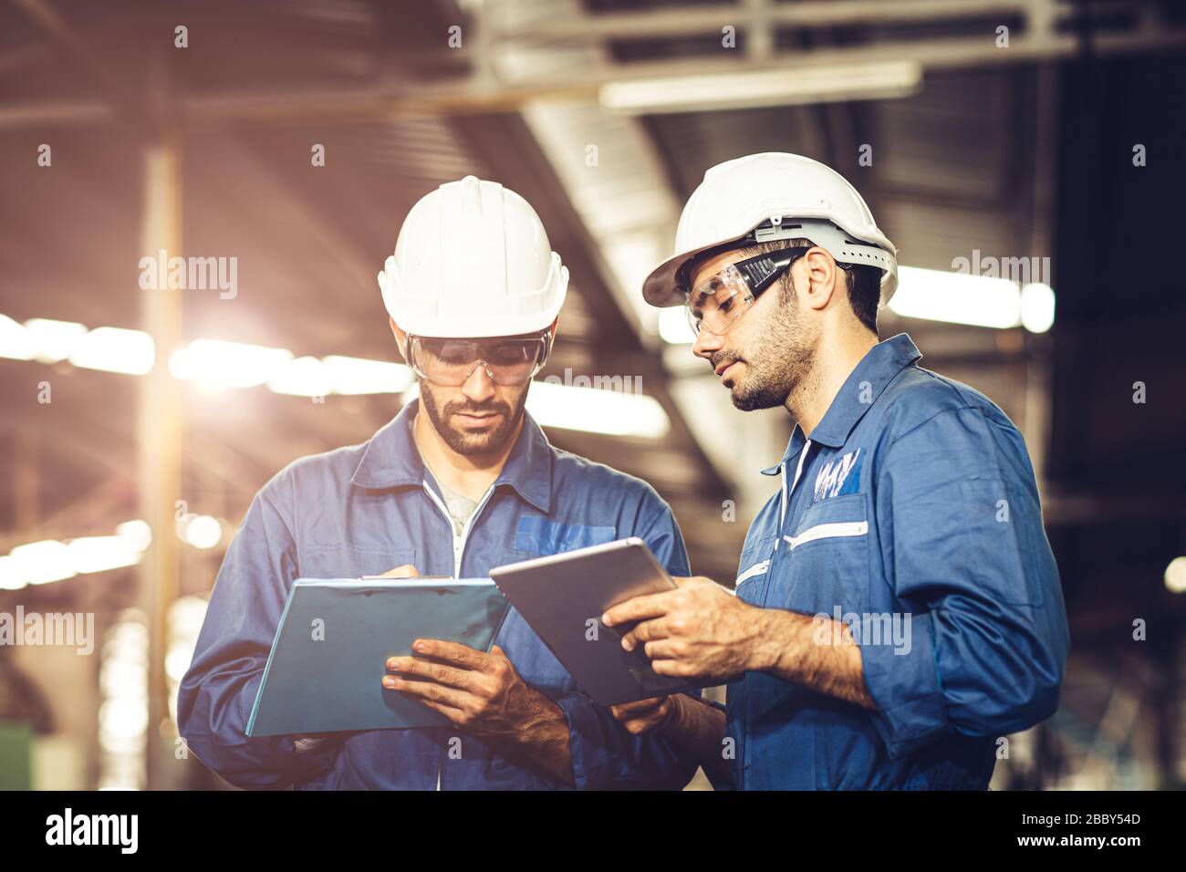 Engineer Audit Worker, das Team mit einem einheitlichen und weißen Helm für die Arbeit in der Industrie arbeitet, bearbeiten Tablette und Checkliste. Stockfoto
