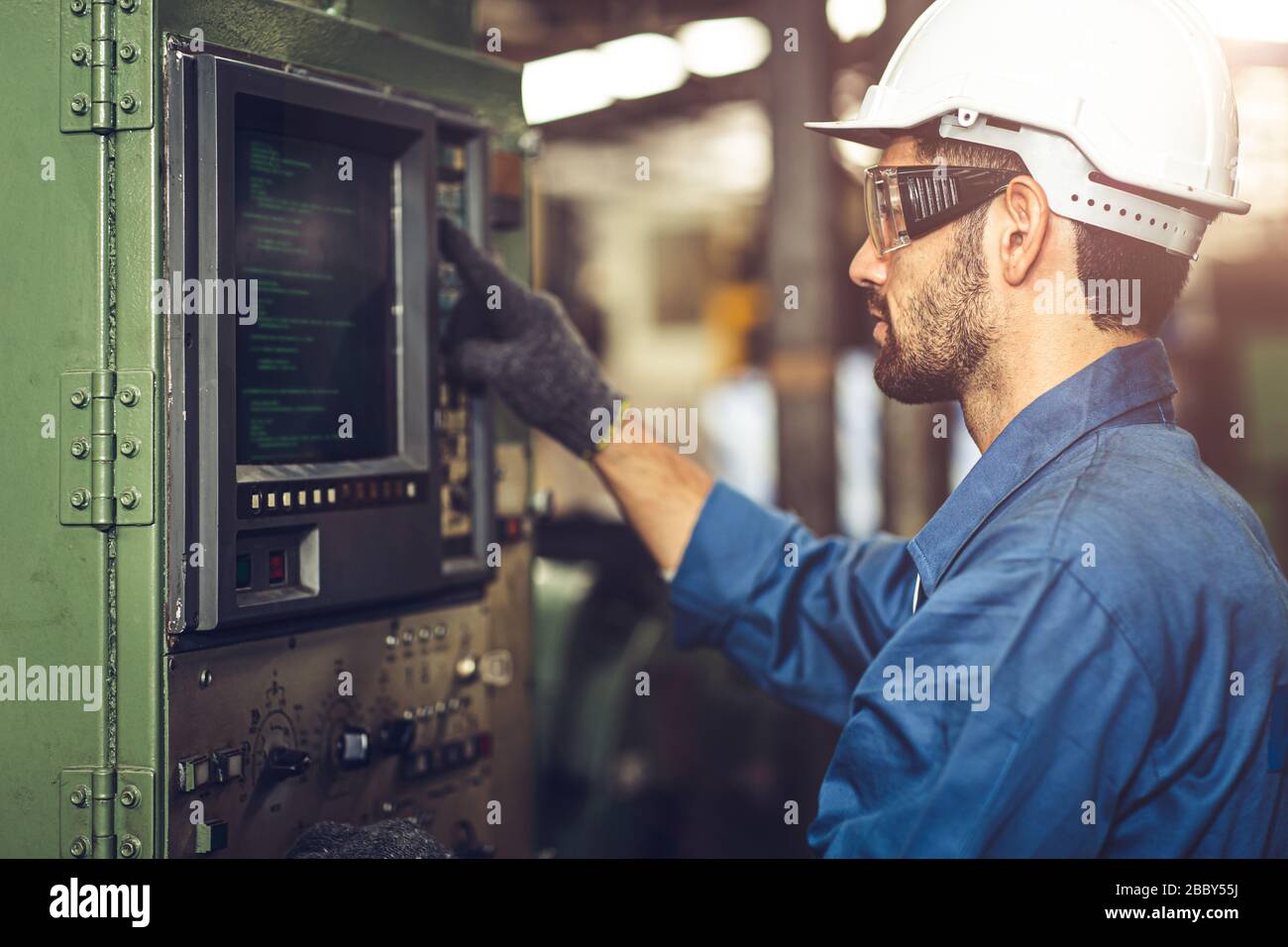 Arbeiter bedienen CNC-Maschine mit G-Code-Monitor, hochqualifizierte Arbeitsbranche mit Sicherheitskleidung. Stockfoto