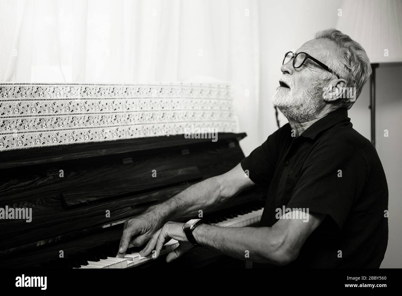 Home Pianist, fröhlicher Ältester spielt Musikklavier mit Stimmungsgeste für den Liedeindruck. Stockfoto