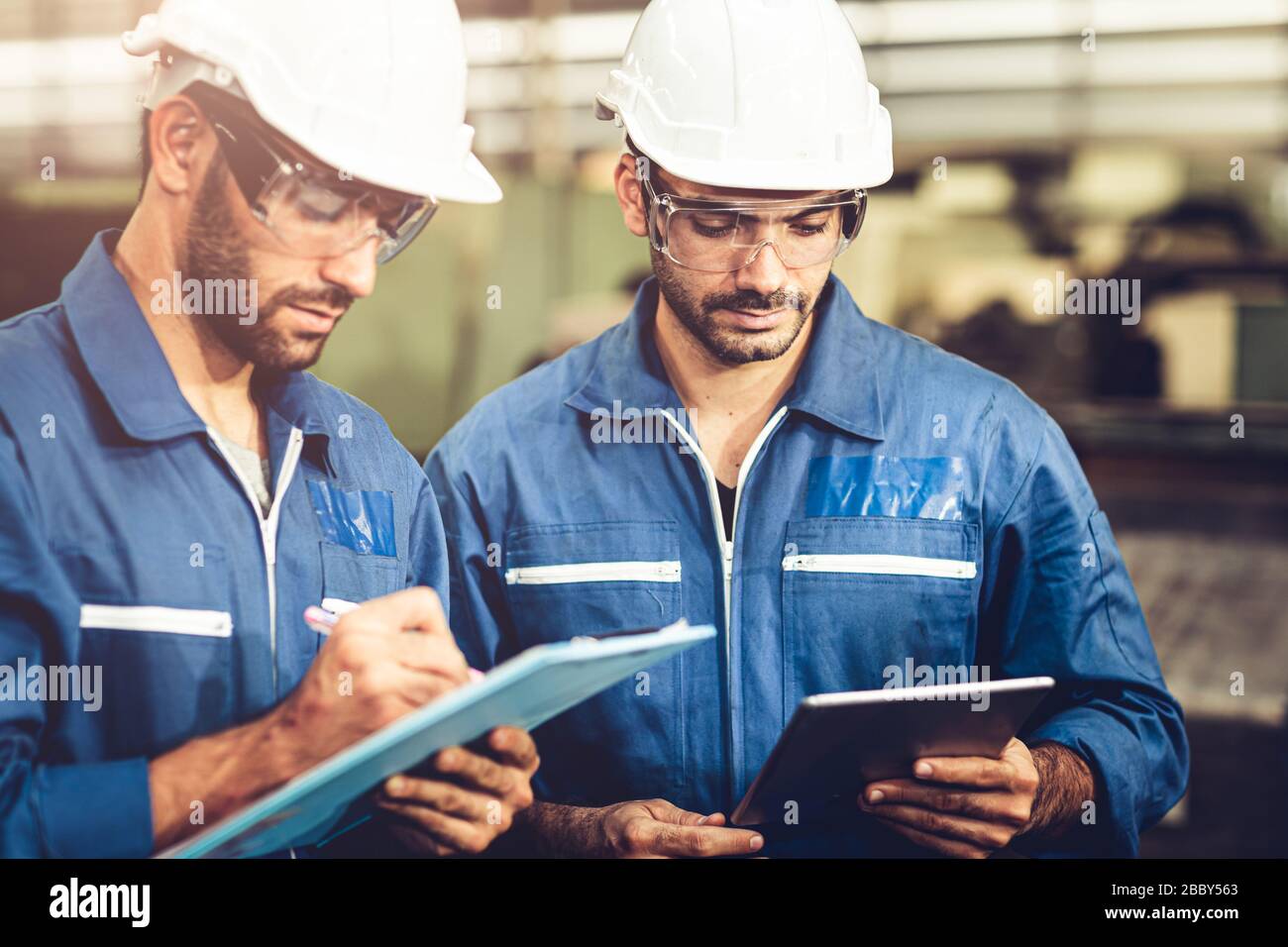 Engineer Audit Worker, das Team mit einem einheitlichen und weißen Helm für die Arbeit in der Industrie arbeitet, bearbeiten Tablette und Checkliste. Stockfoto