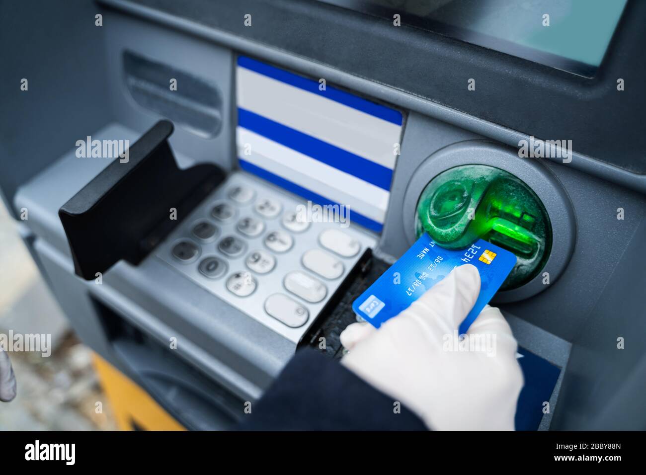 Tragen von Handschuhen beim Einsatz von ATM zum Schutz vor Coronavirus Infektionen Stockfoto