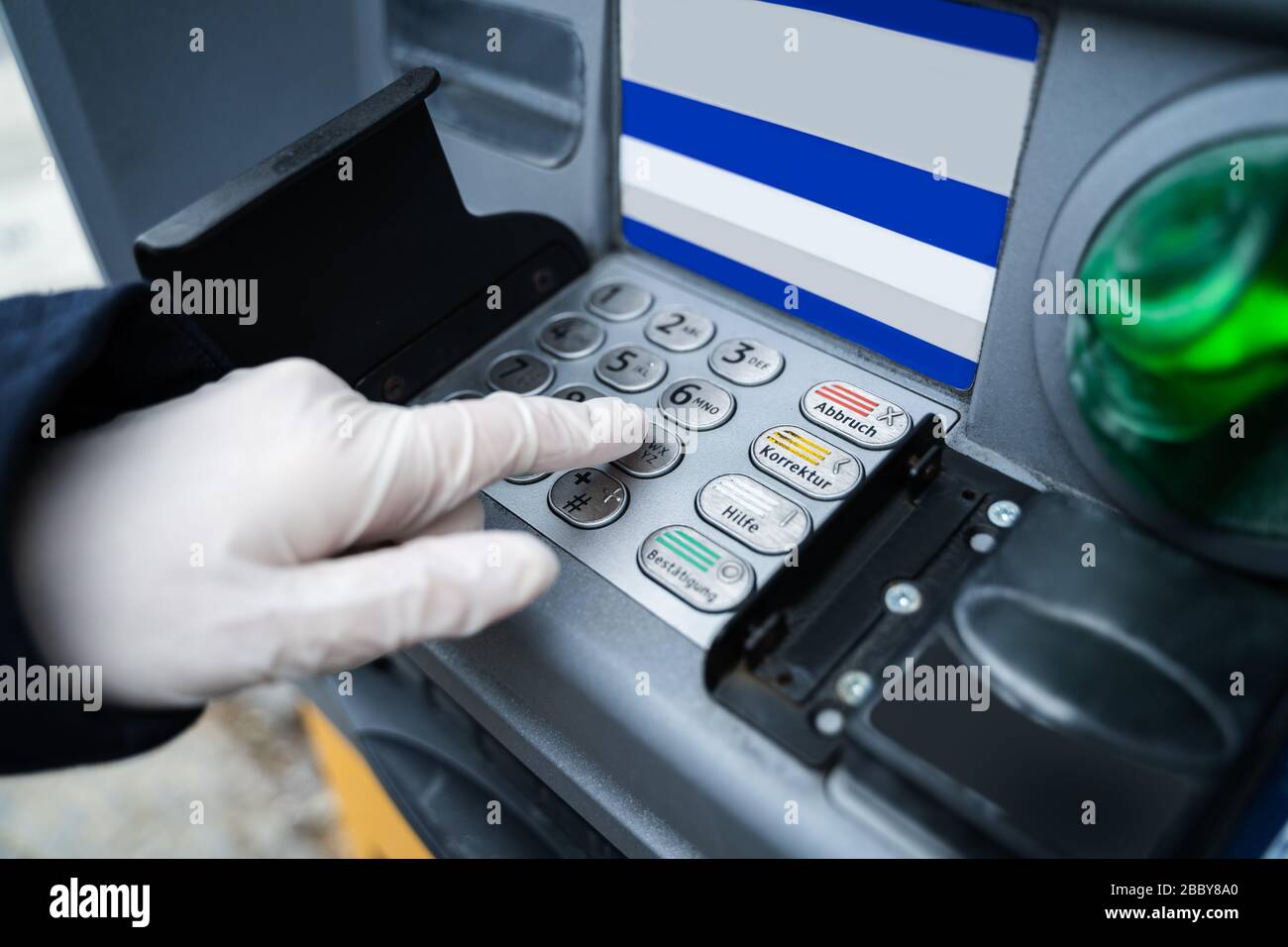 Tragen von Handschuhen beim Einsatz von ATM zum Schutz vor Coronavirus Infektionen Stockfoto