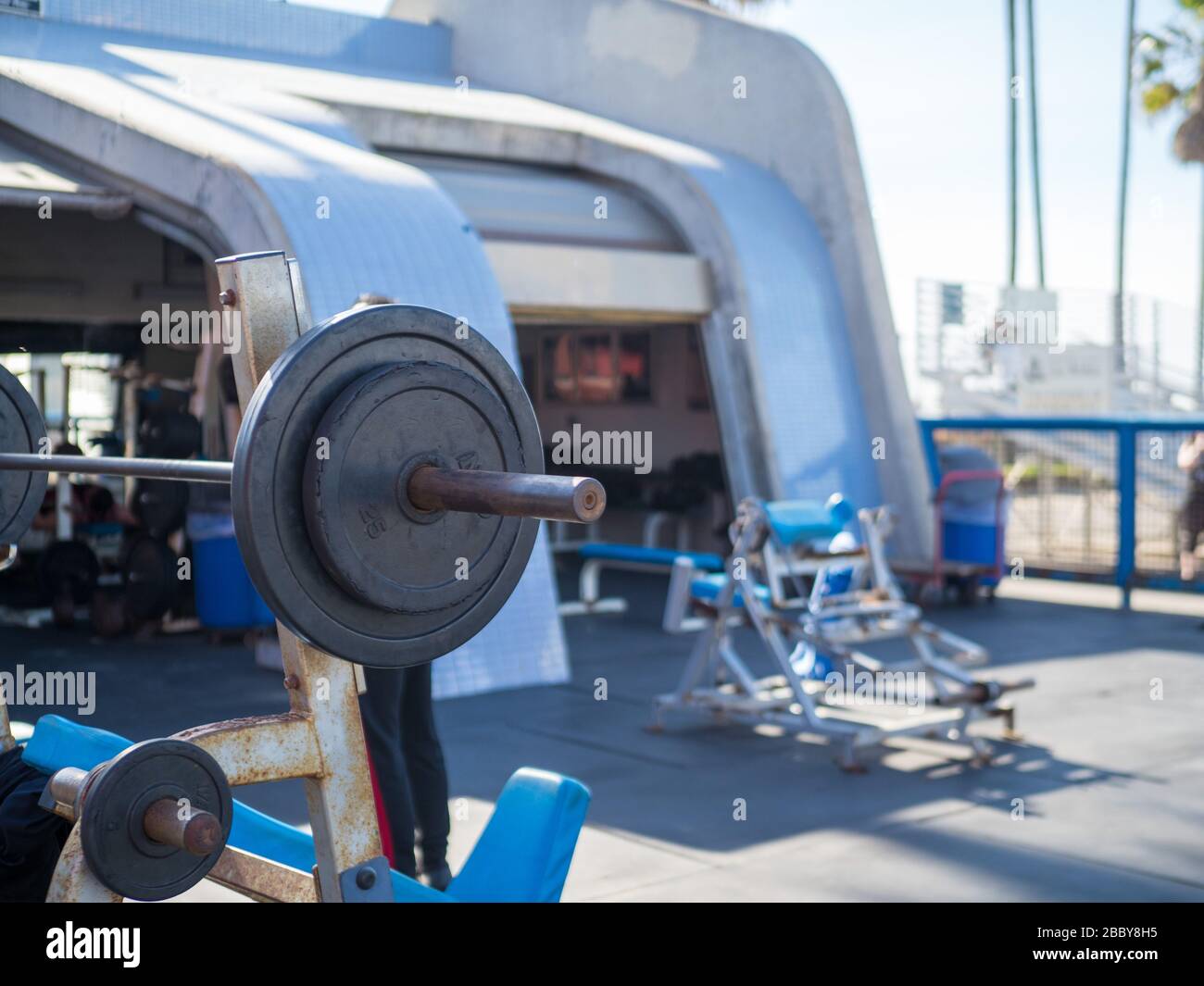 Rack mit umgedrehter Tischpresse mit Barbell und 45 und 25 lb Gewicht rostiger Sporthalle im Freien Stockfoto
