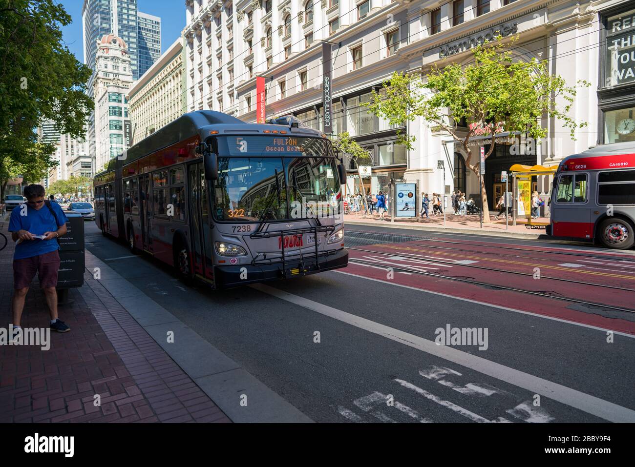 MUNI Bus Fulton Linie 5 auf dem Umzug hinter Person auf dem Market Street Einkaufsviertel Stockfoto