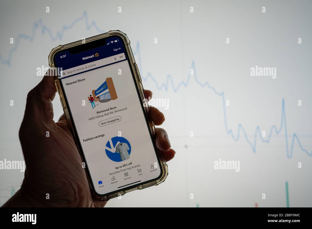 Walmart Mobile App auf dem iPhone vor der weißen Börsenkarte mit Grafik im Wert Stockfoto