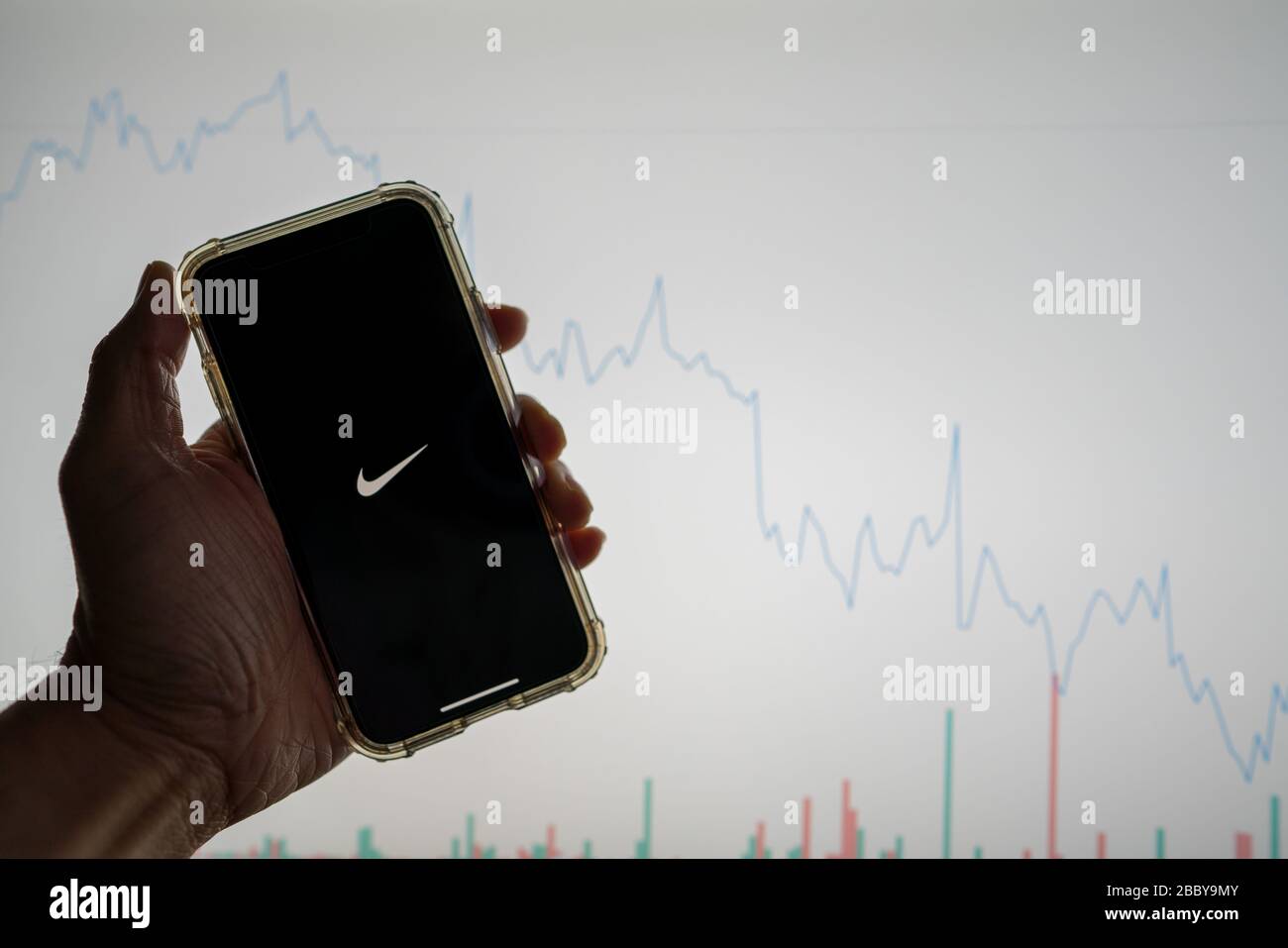 Das Nike Mobile App Logo auf dem iPhone vor der weißen Börsenkarte mit einem Diagramm, das den Wert abgesenkt hat Stockfoto