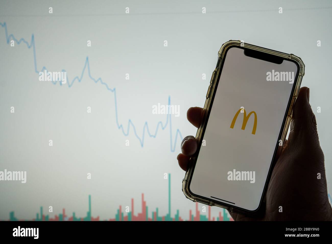 McDonald s-Logo für mobile Apps auf dem iPhone vor der weißen Börsenkarte mit einem Diagramm, das den Wert abgesenkt hat Stockfoto
