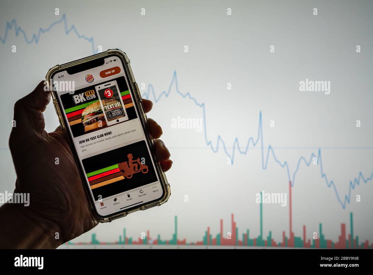 Burger King Mobile App mit Angeboten auf dem iPhone vor der weißen Börsenkarte mit einem Diagramm, das den Wert nach unten zeigt Stockfoto