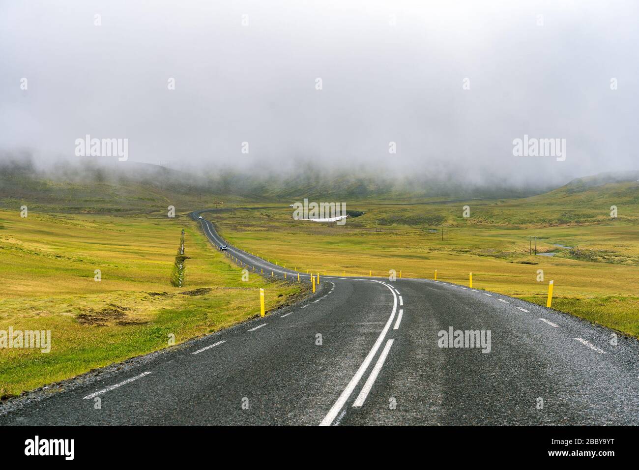 In den Hochbergen Islands wolken sich niedrige Nebelschwaden über die Straße Stockfoto