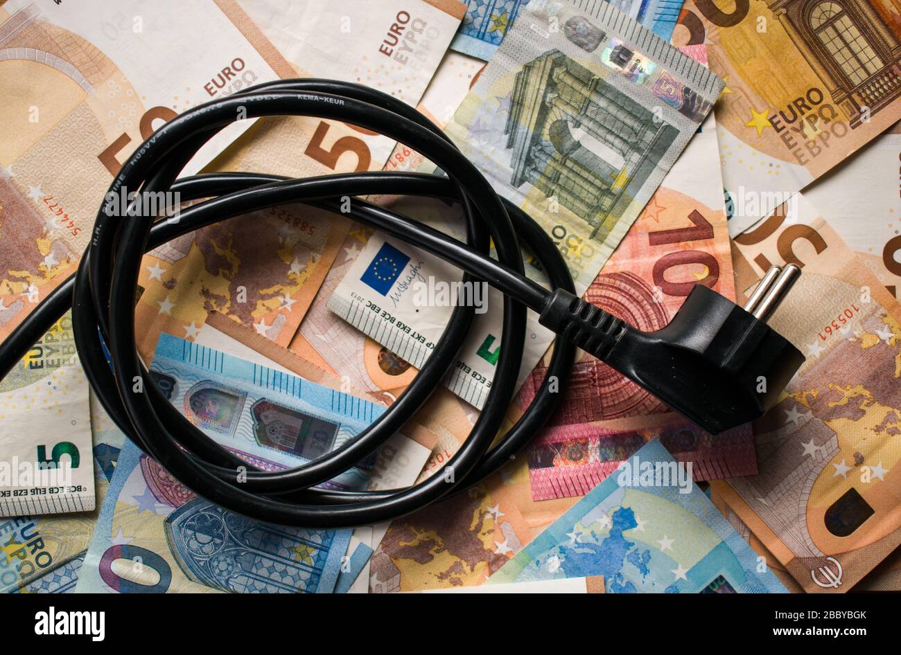Schwarzer Stromstecker auf Euro-Papiergeld. Stromkosten, Sparkonzept Stockfoto