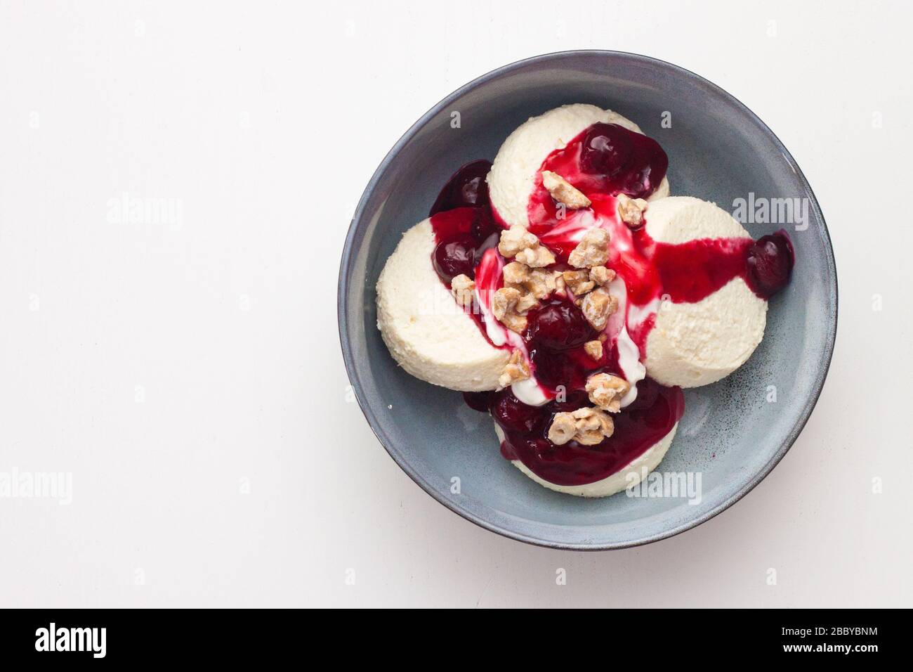 Käsekäse oder Pfannkuchen mit Kirschsoße und gehackten Nüssen auf weißem Hintergrund. Isoliert. Stockfoto