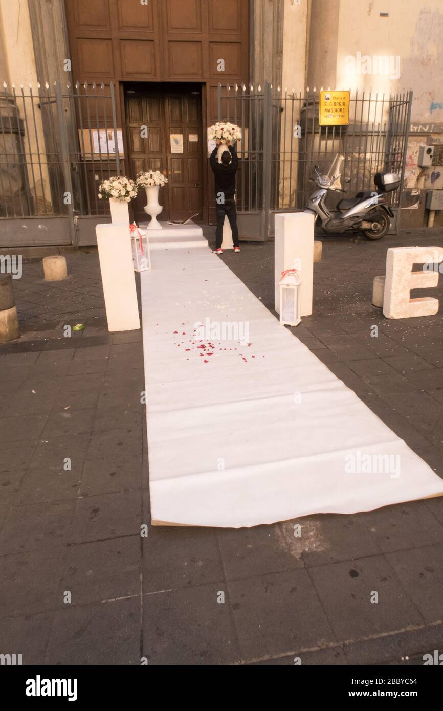 Ein Mann, der Blumen vor einer Kirche arrangiert, während er auf eine Hochzeit wartet Stockfoto