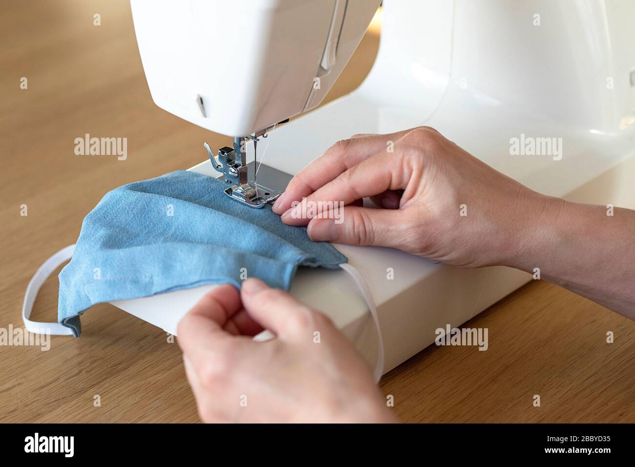 Arbeitsprozess, Nähmasken zum Schutz, Frau händigt Gesichtsmasken an der Nähmaschine aus, da es während der Kovid-19-Krise an Material mangelte Stockfoto