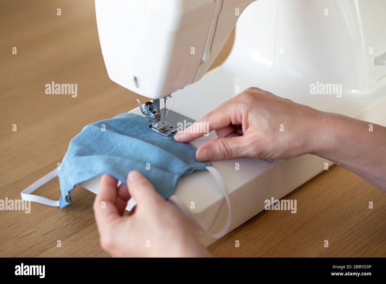 Arbeitsprozess, Nähmasken zum Schutz, Frau händigt Gesichtsmasken an der Nähmaschine aus, da es während der Kovid-19-Krise an Material mangelte Stockfoto