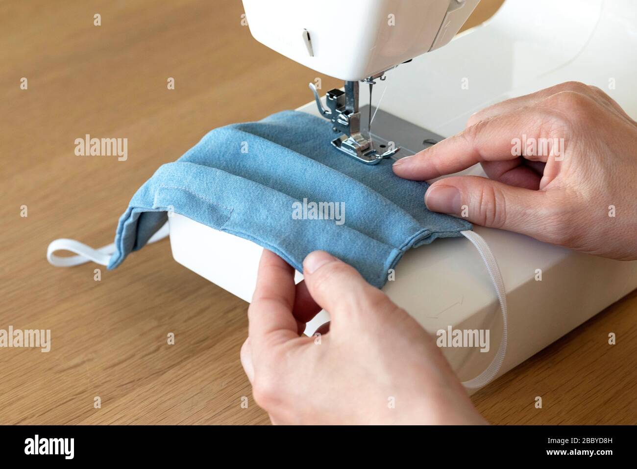 Arbeitsprozess, Nähmasken zum Schutz, Frau händigt Gesichtsmasken an der Nähmaschine aus, da es während der Kovid-19-Krise an Material mangelte Stockfoto