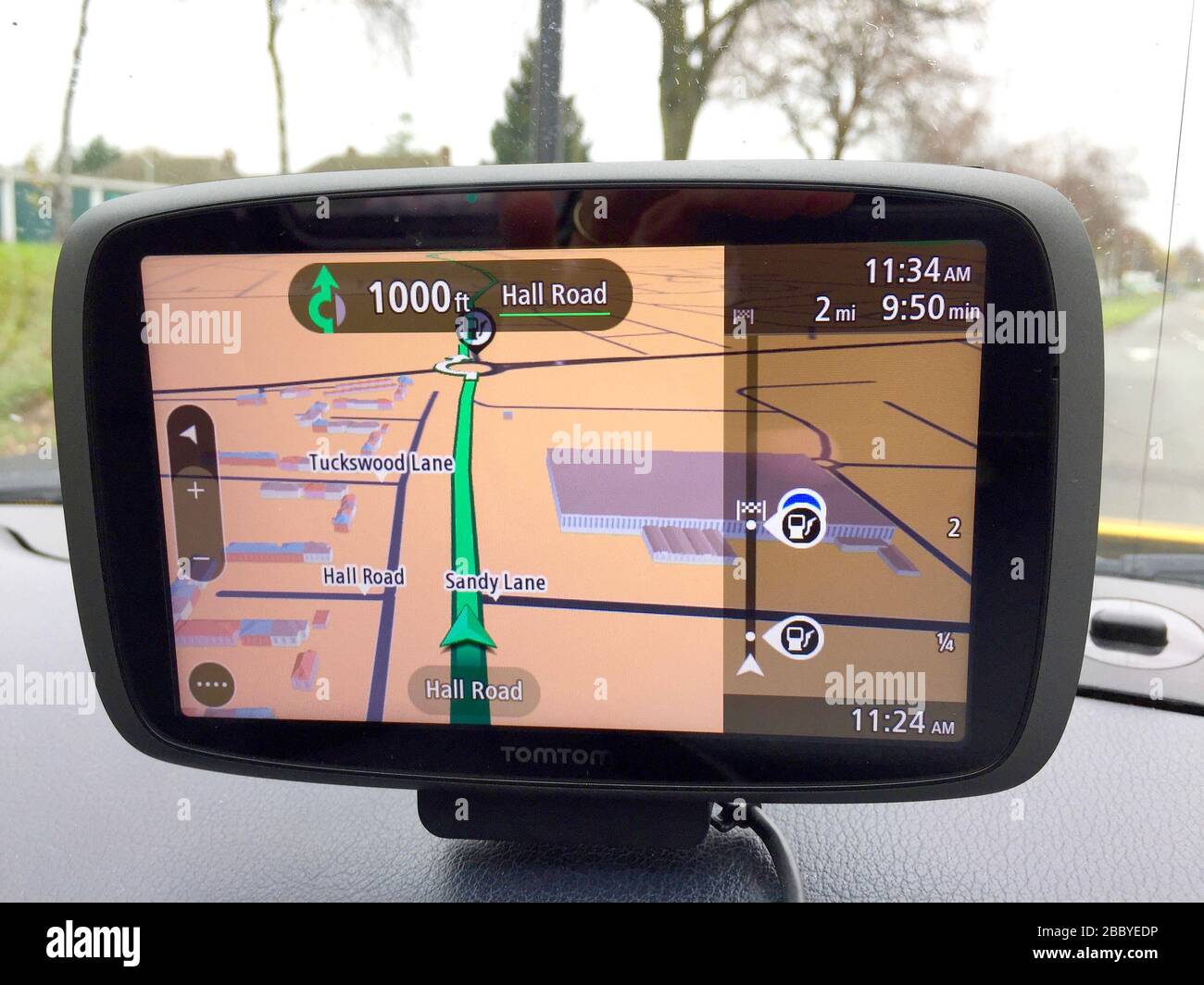 Am Armaturenbrett montierte Satellitennavigationseinheit mit Blick auf die Straße durch die Windschutzscheibe. Stockfoto