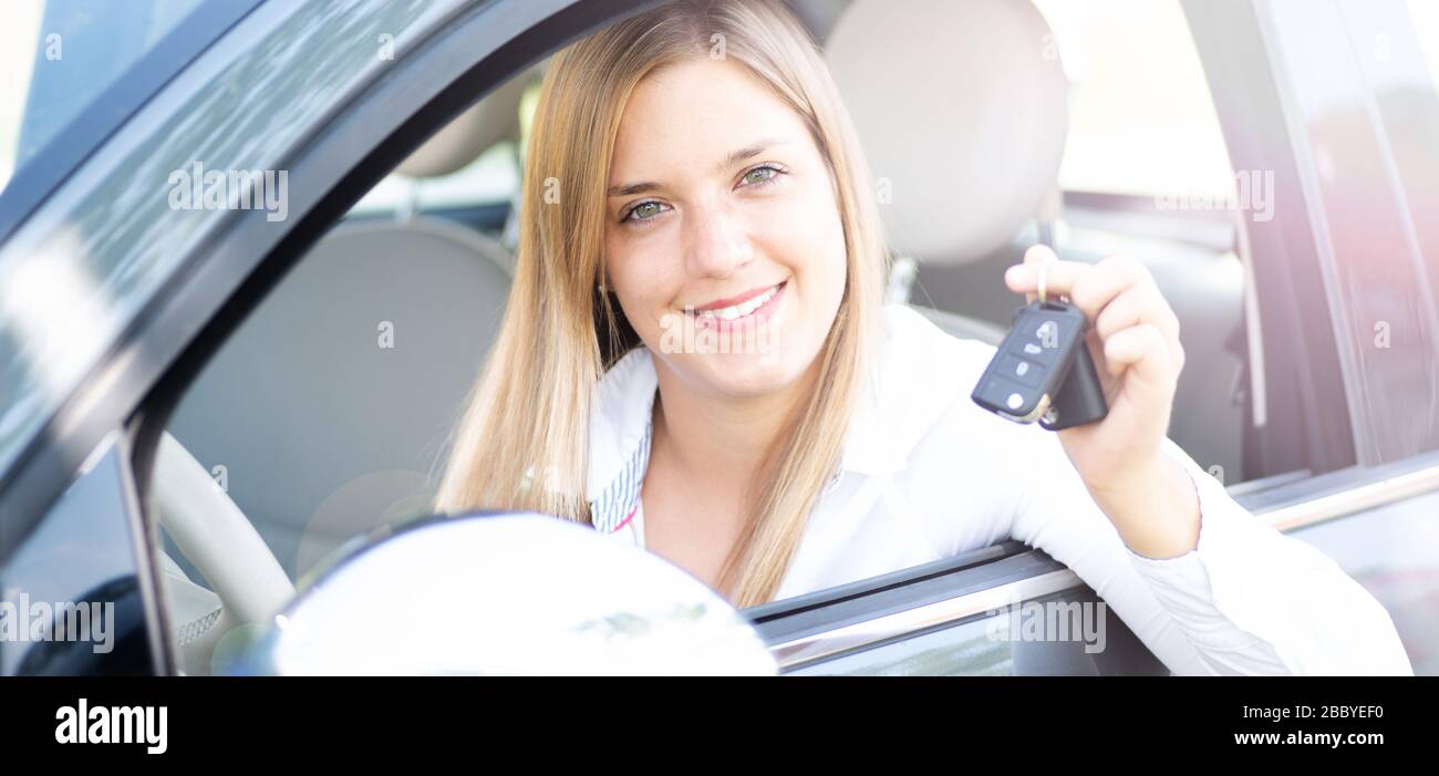 Die junge Frau zeigt stolz die Schlüssel ihres ersten Autos Stockfoto