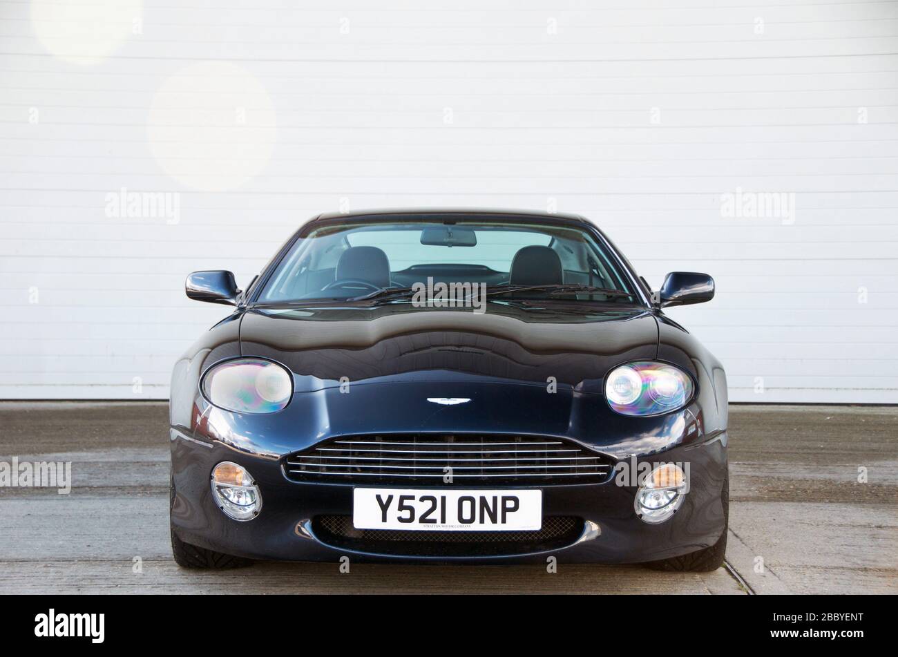 Das dunkelblaue Aston Martin DB7 Vantage Coupé hat vorne mit interessanten Reflexen auf der Motorhaube gedreht. Stockfoto