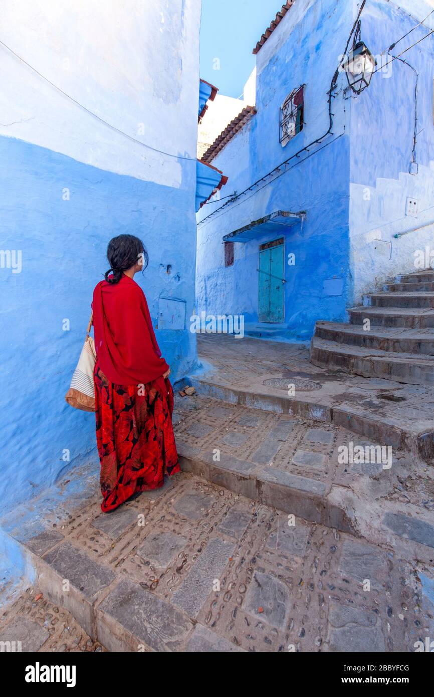 Chefchaouen, Marokko: Eine Frau in Rot, die in der Medina spaziert Stockfoto