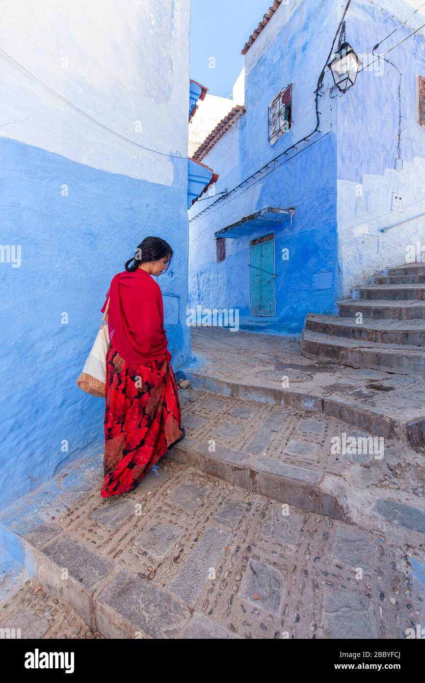 Chefchaouen, Marokko: Eine Frau in Rot, die in der Medina spaziert Stockfoto