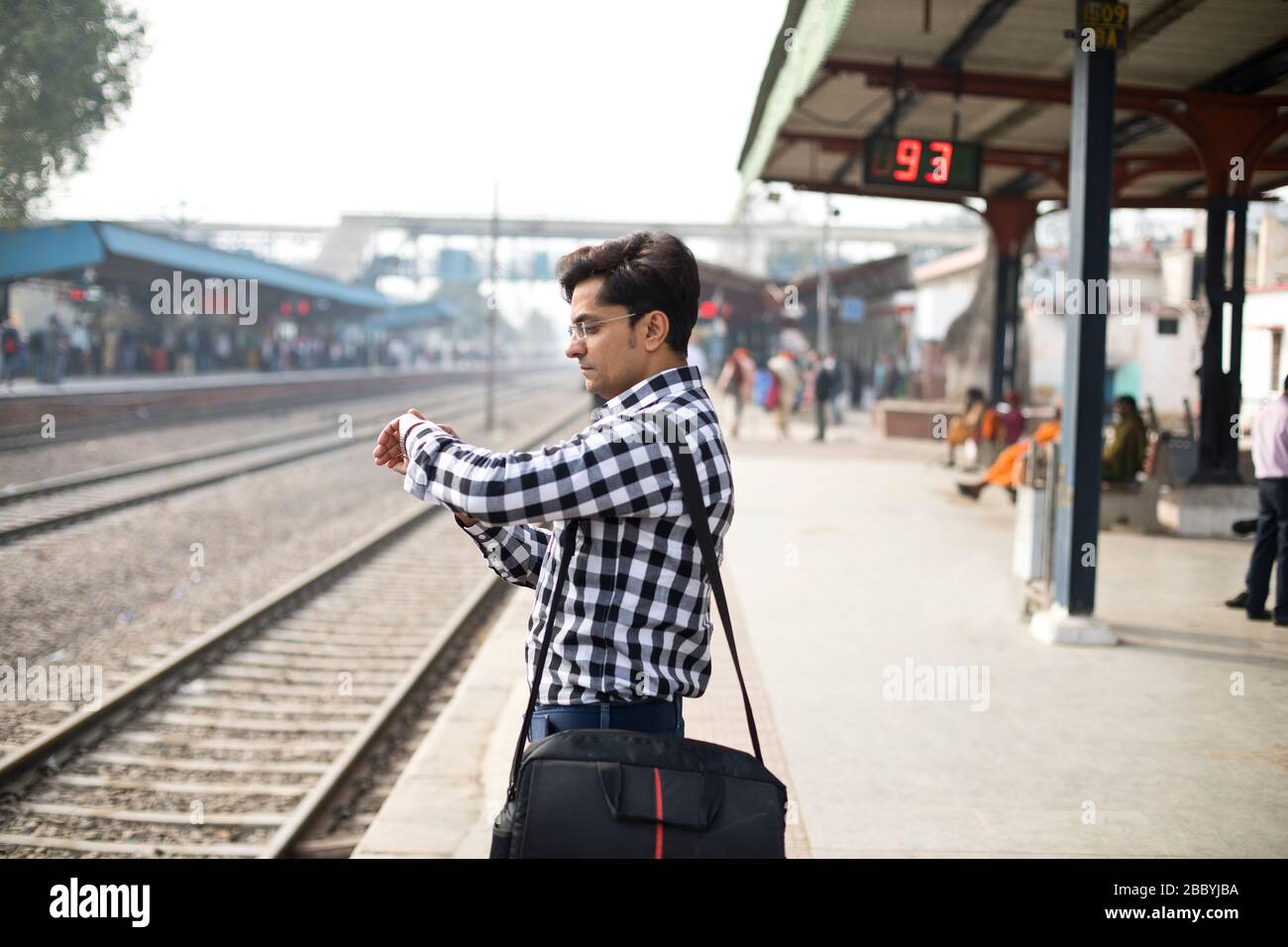 Mann überprüft die Zeit, während er am Bahnhof wartet Stockfoto
