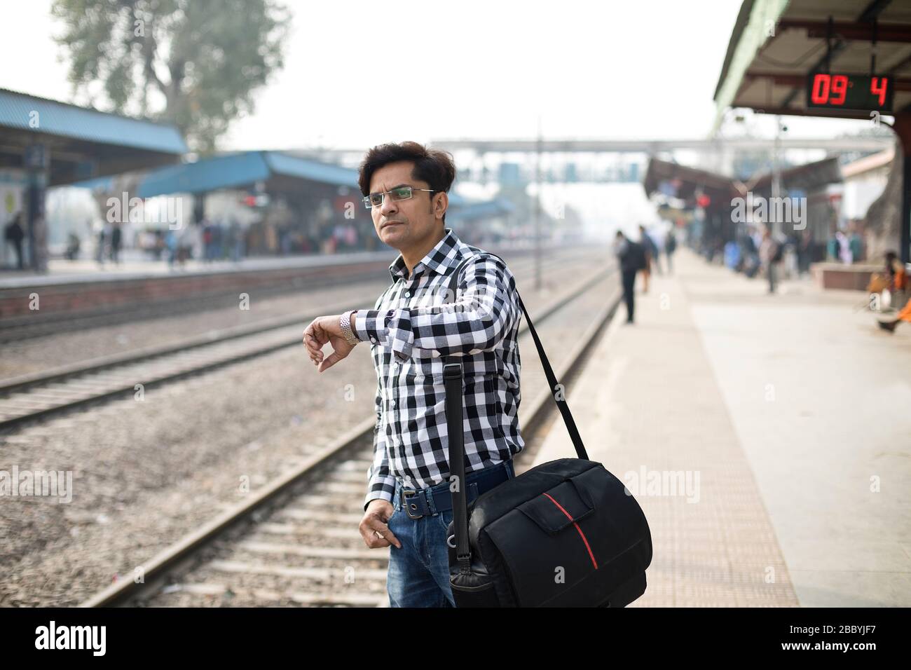 Mann überprüft die Zeit, während er am Bahnhof wartet Stockfoto