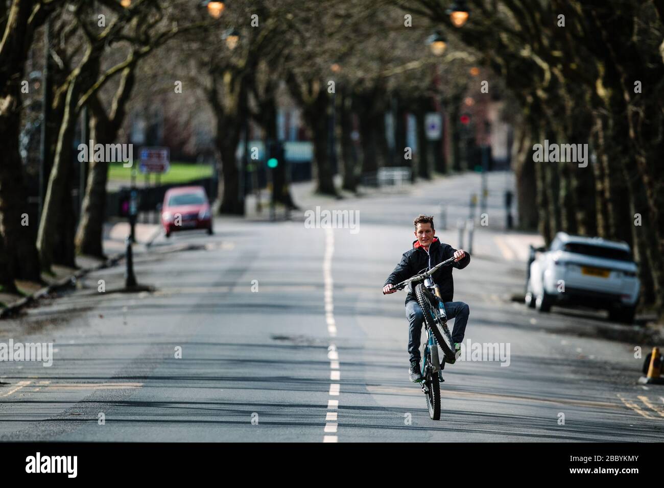 Radfahrer macht während des Corona-Virus-Lockdowns einen Roller auf einer ruhigen Glasgower Straße. Stockfoto