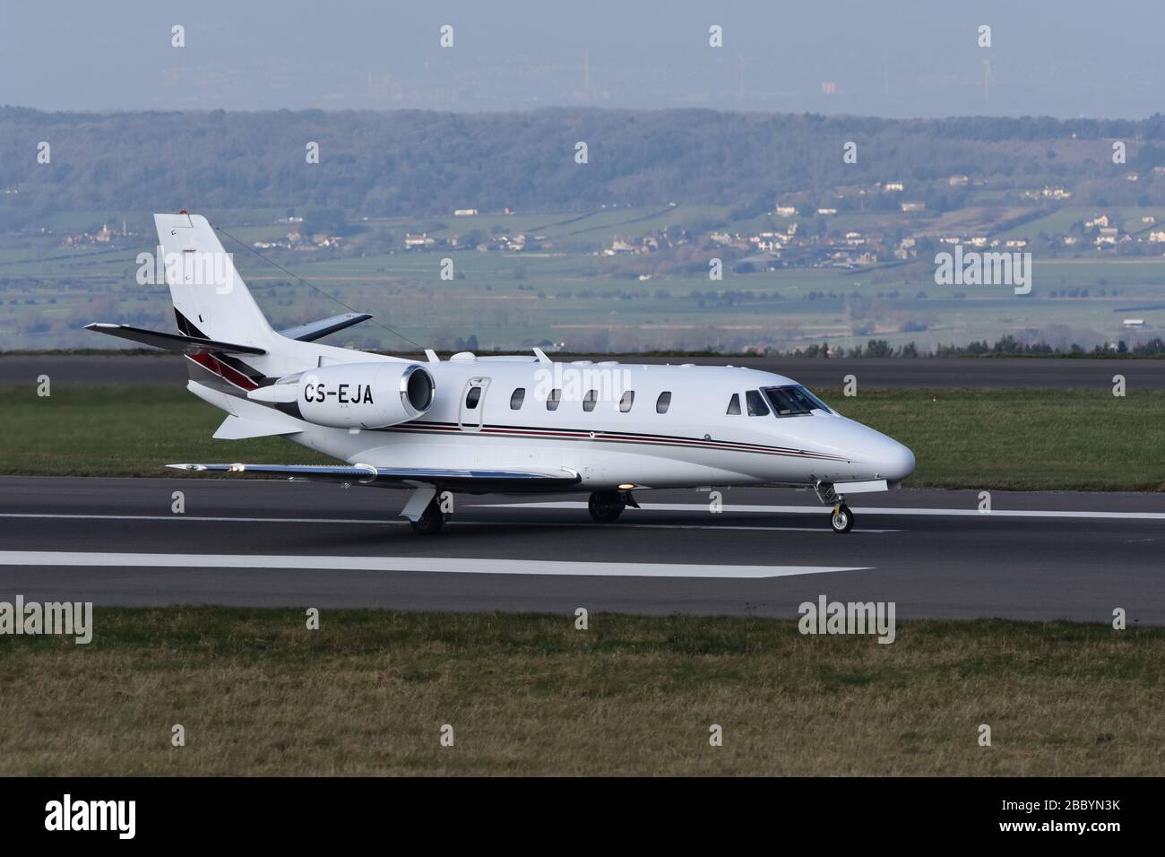 Ein Privatjet, der die Landebahn am Bristol International Airport (UK) hinunter fährt, wird gerade abfahren, mit einem schönen Hintergrund. Foto aufgenommen - Winters Lane Stockfoto