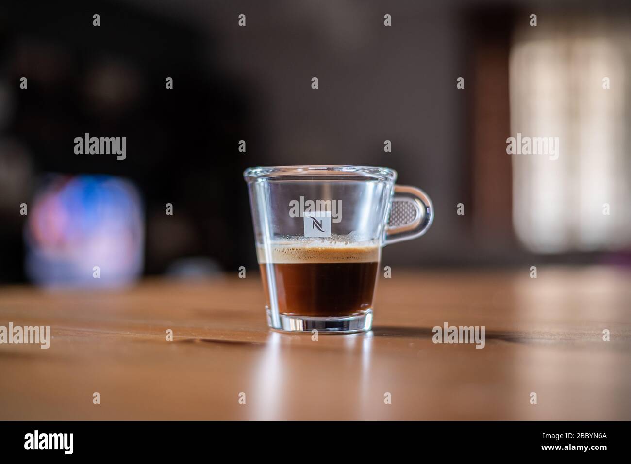 Transparentes Nespresso-Glas Kaffee auf einem Tisch mit verschwommenem Hintergrund Stockfoto