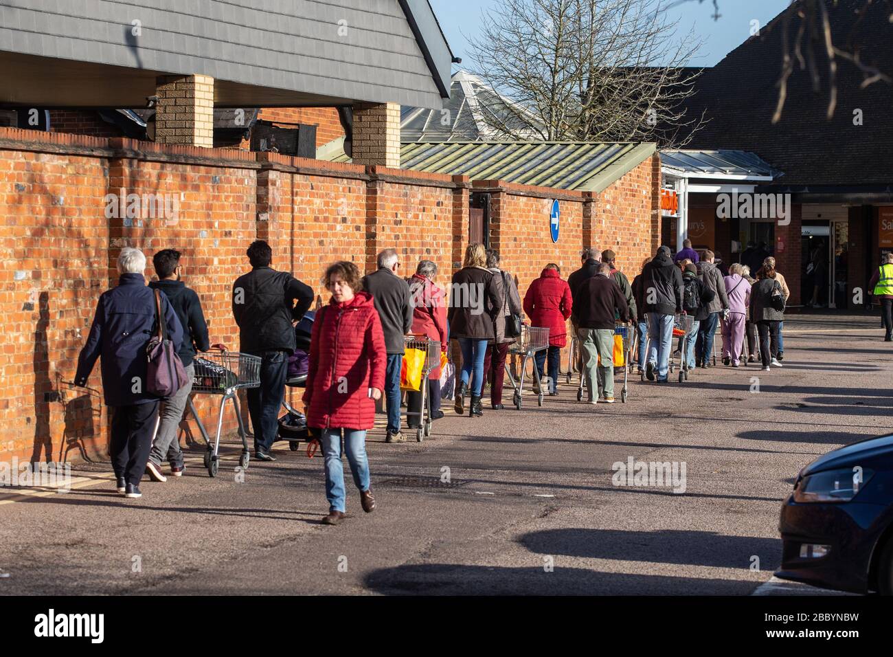 Leute, die Schlange stehen, um während Coronavirus Panikkauf im Vereinigten Königreich März 2020 einen Supermarkt zu betreten Stockfoto