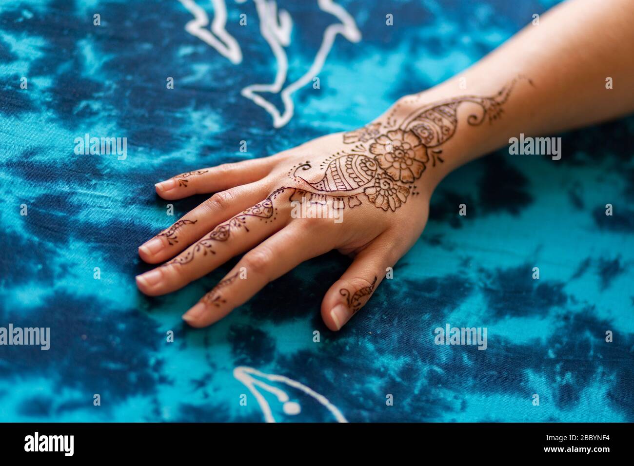 Henna Kunst-Tattoo auf weiblicher Hand mit blauem Hintergrund Stockfoto
