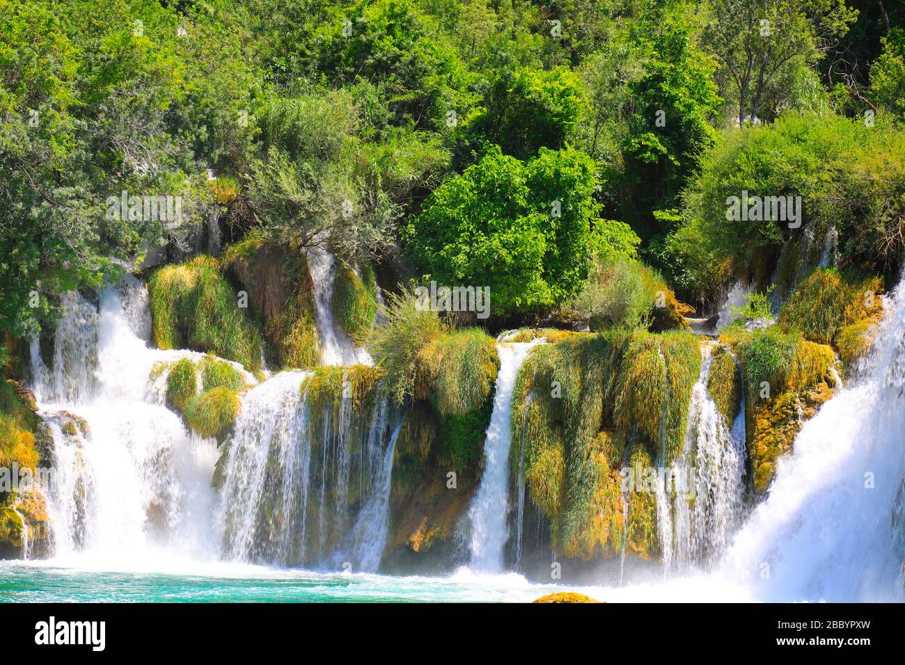 Ein malerischer Kaskadenwasserfall unter großen Steinen im Landschaftspark Krka, Kroatien im Frühjahr oder Sommer. Die besten großen, wunderschönen kroatischen Wasserfälle Stockfoto