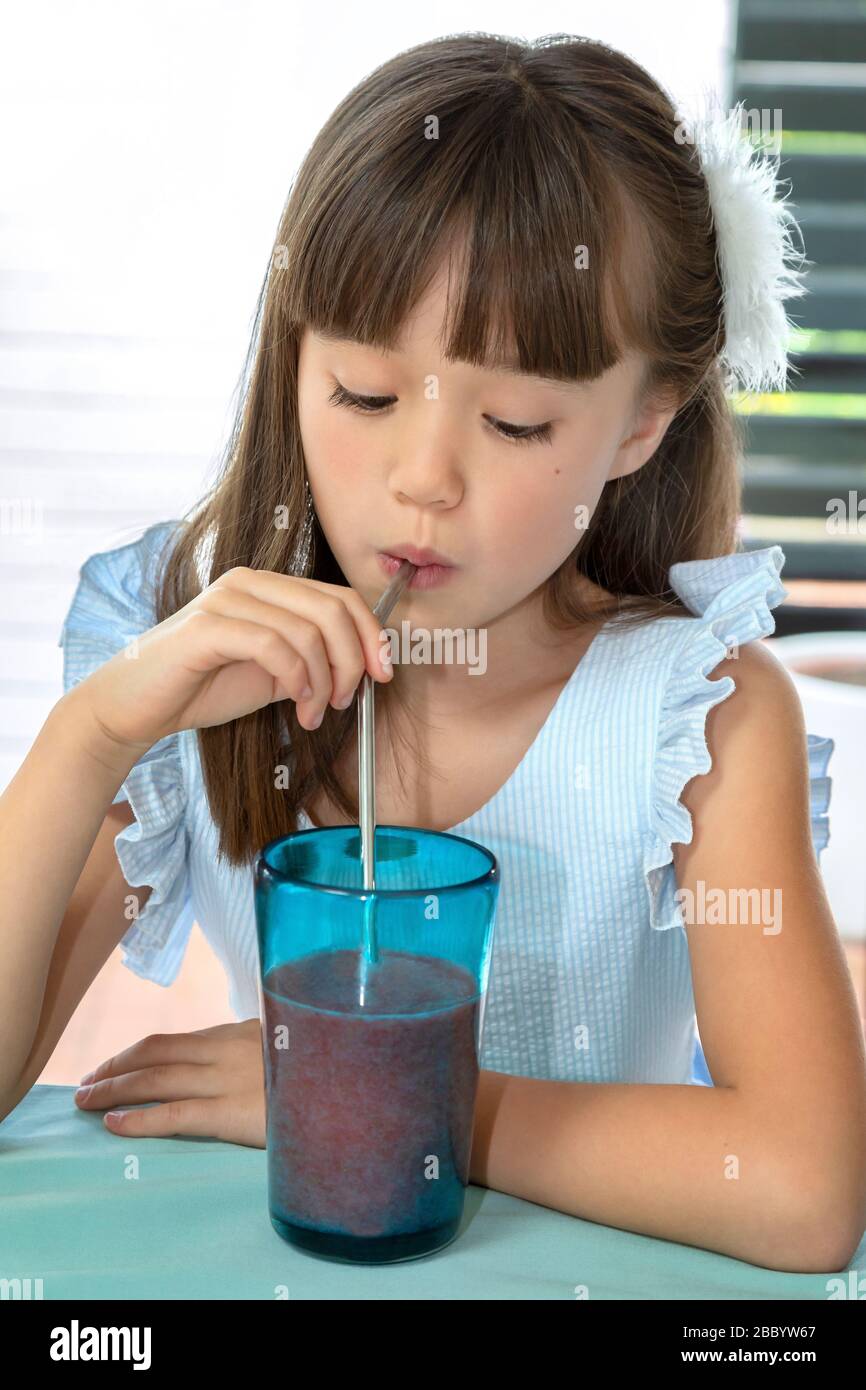Acht Jahre altes Mädchen, das aus einem Metallstroh trinkt Stockfoto