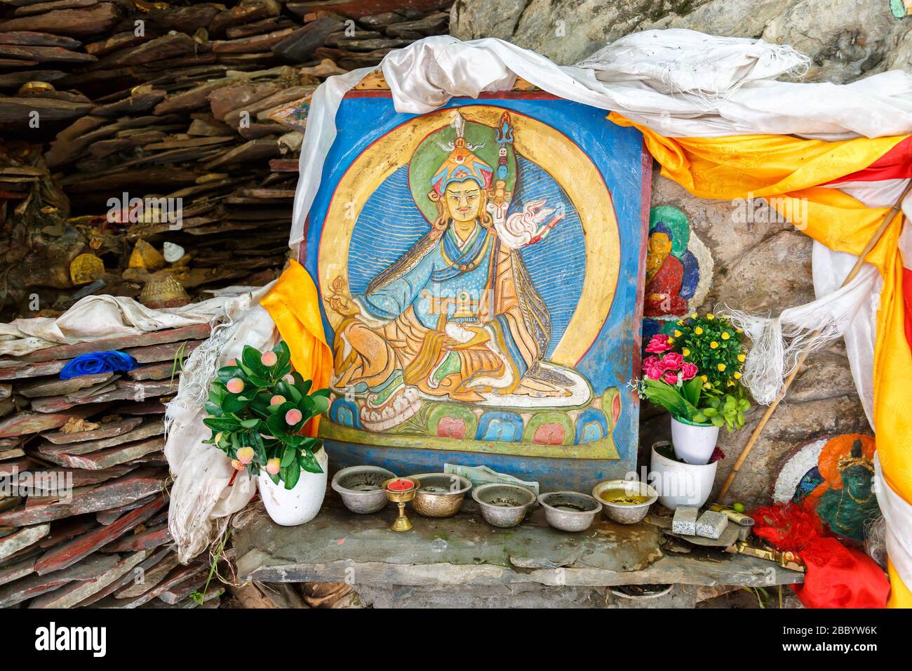 Farbenfrohe Malerei einer Gottheit des tibetischen buddhismus. Im Freien in einem Gebiet in der Nähe von Potala Palace. Mit Blumen und anderen Angeboten. Tibetische Kunst Stockfoto